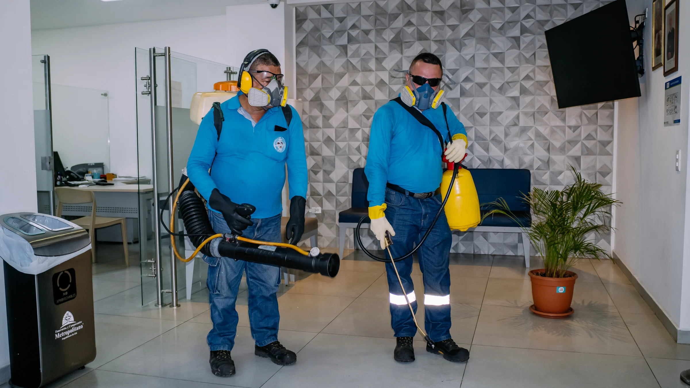 Dos tecnicos de control de plagas trabajando en unas oficinas en Cali